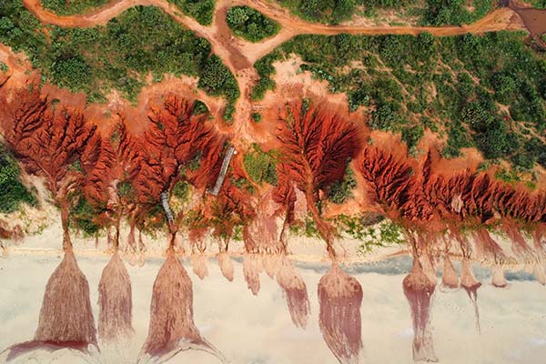 Green landscape gives way to red sand hills and the coast