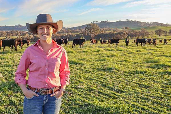 Emily Greer standing in paddock wth cattle in background
