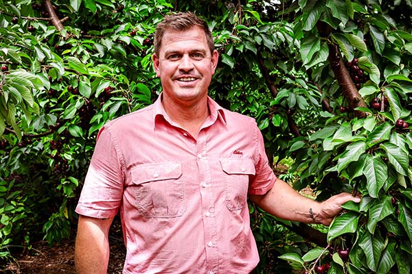 Lucas Coreejes standing in front of a bushy tree