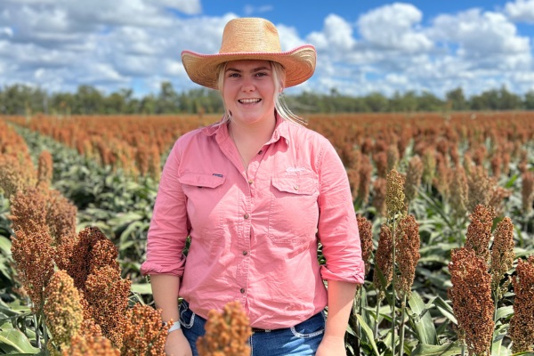 Agronomist Grace McDonald standing ina field of sorghum smiling at camera
