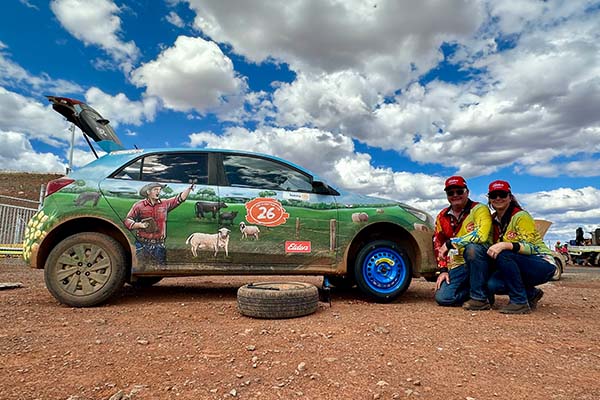 Two staff change a flat tyre on the Elders decorated car in the Dirt n Dust Run 2026